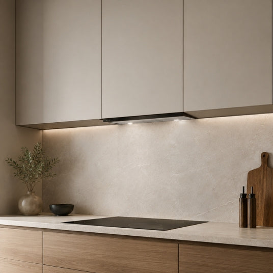 Aufgeräumte moderne Küchenzeile mit geschlossenen Oberschränken und kaum sichtbarer Schrankhaube. Nur die schmale Frontleiste unter den Hängeschränken ist erkennbar und fügt sich dezent in das elegante Küchendesign ein.