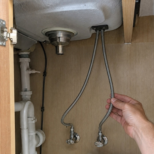 Großzügig und flexibel verlegte Anschlussschläuche im Spülenunterschrank für eine bewegliche Vorfenster-Armatur.